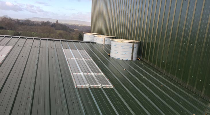 Three cylinder shaped flu stacks protruding from roof cladding