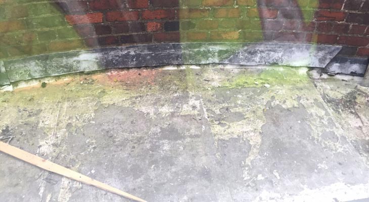 Old delaminating flat roof area with failing lead counter flashing