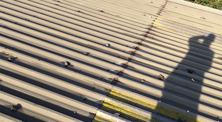 Industrial roof showing cut edge corrosion and impact damage from rocks