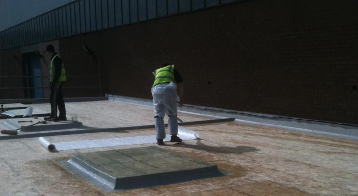 GRP roofing installer rolling out fleece during the resin stage