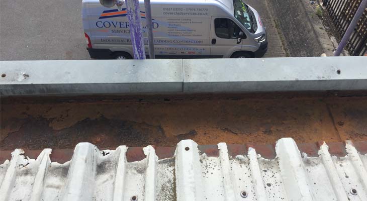 Cut edge corrosion and heavily corroded gutter with Coverclad van in the background