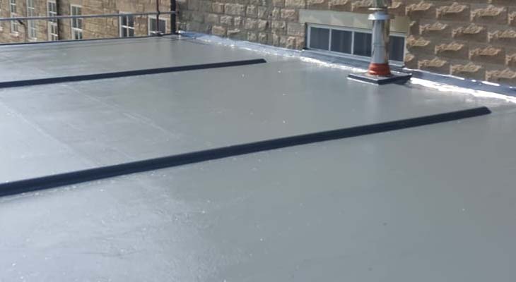 Dark grey GRP top coat rolled out across new flat roof